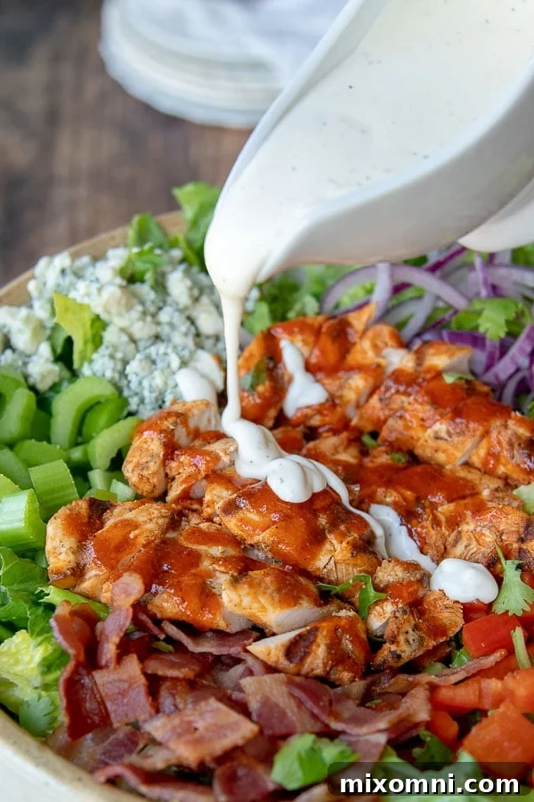 ranch dressing being poured over buffalo chicken salad, showcasing a vibrant and appealing meal