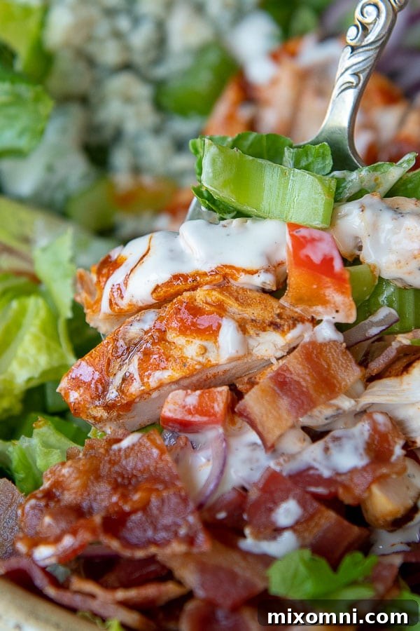 a close up of chicken tossed with ranch and buffalo sauce on the salad, highlighting the vibrant colors and textures