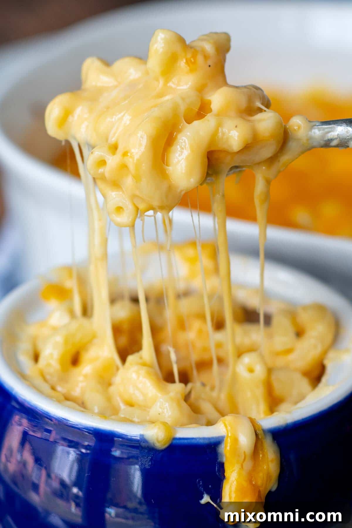 a spoon lifting out a bite of mac and cheese from a blue bowl