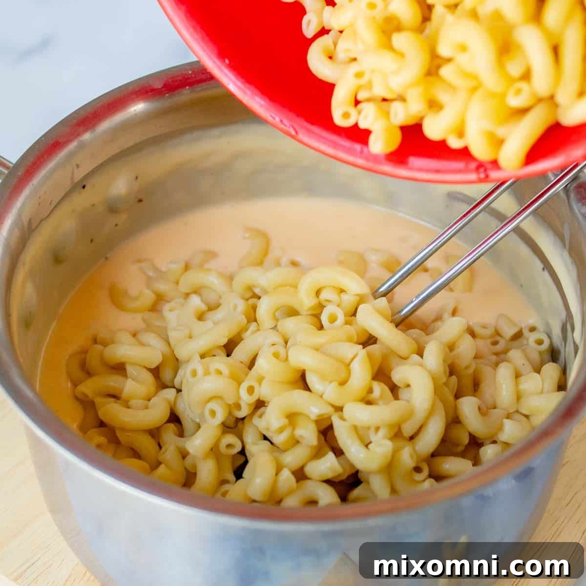 the cooked pasta being added to the cream sauce.