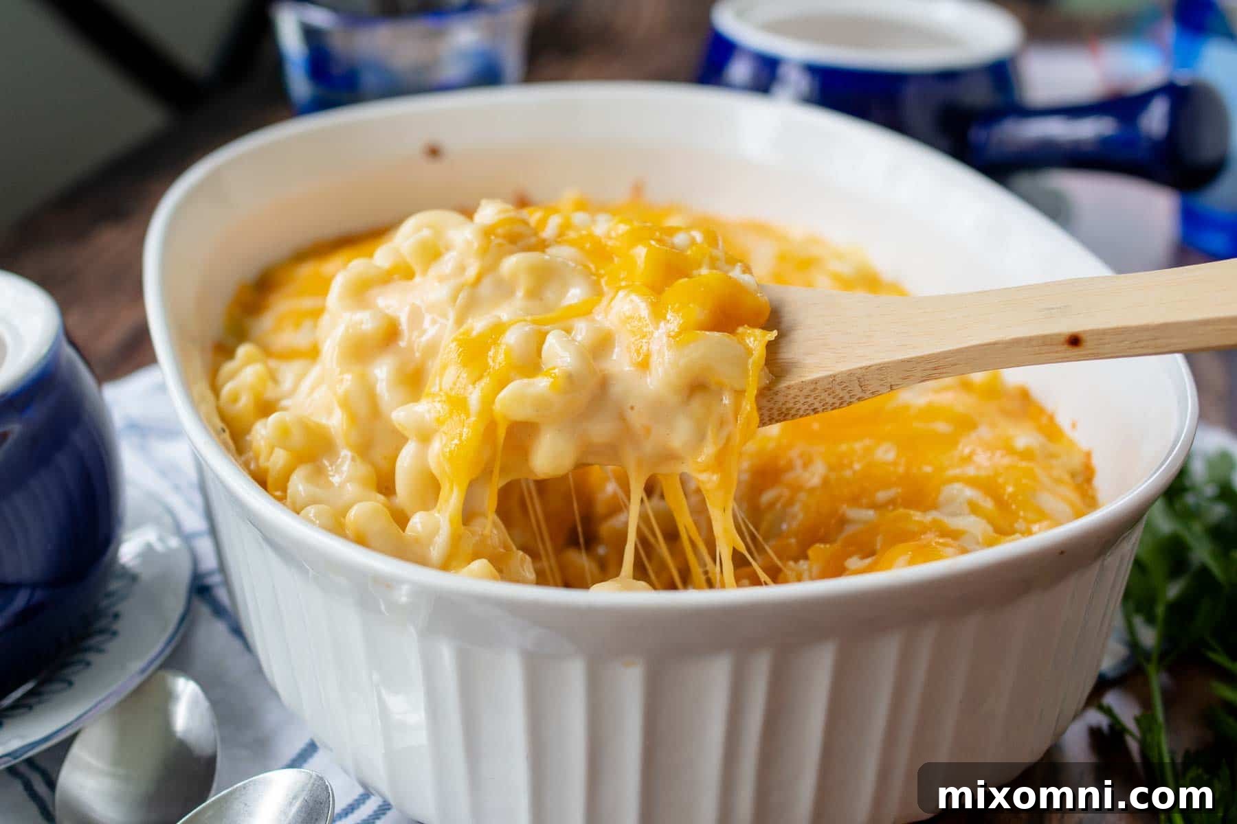 casserole dish with a wooden spoon scooping out mac and cheese