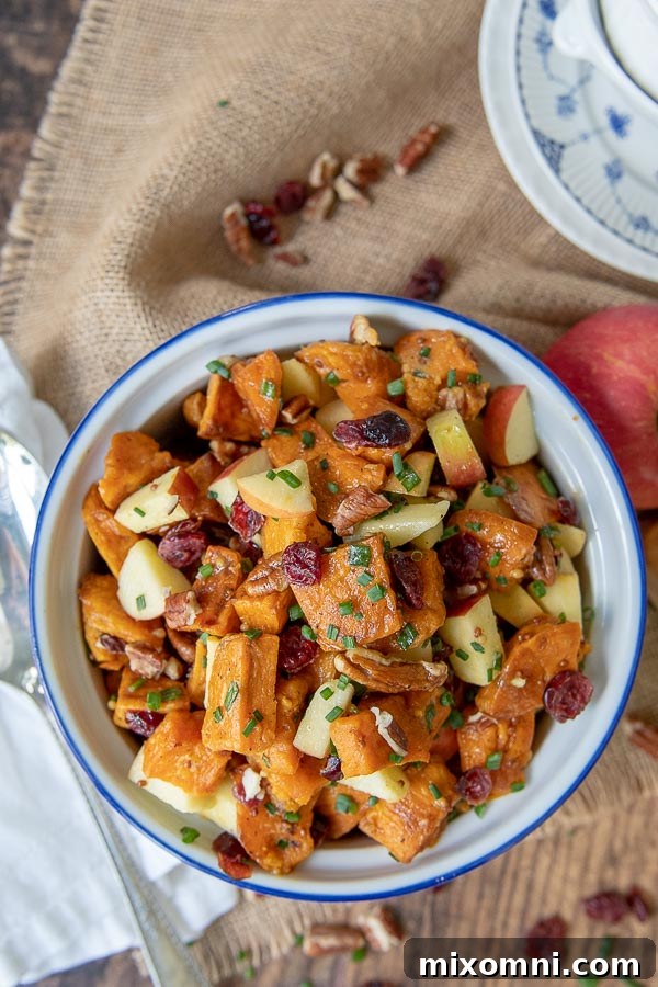 overhead shot of roasted sweet potato salad with a serving spoon and apple resting by