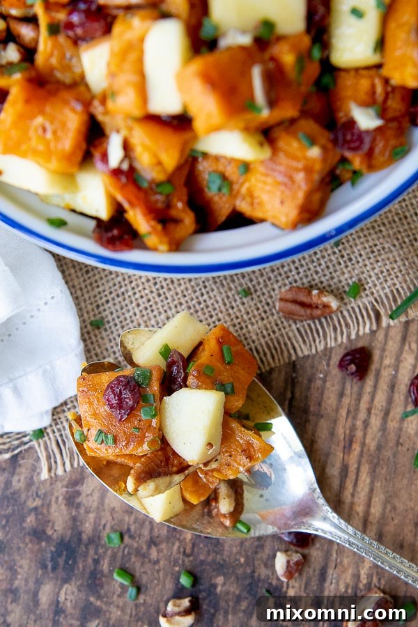an antique silver spoon resting on a wooden table with a scoop of sweet potato salad on the spoon