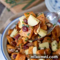 an antique silver spoon holding up a serving of sweet potato salad recipe from a serving dish