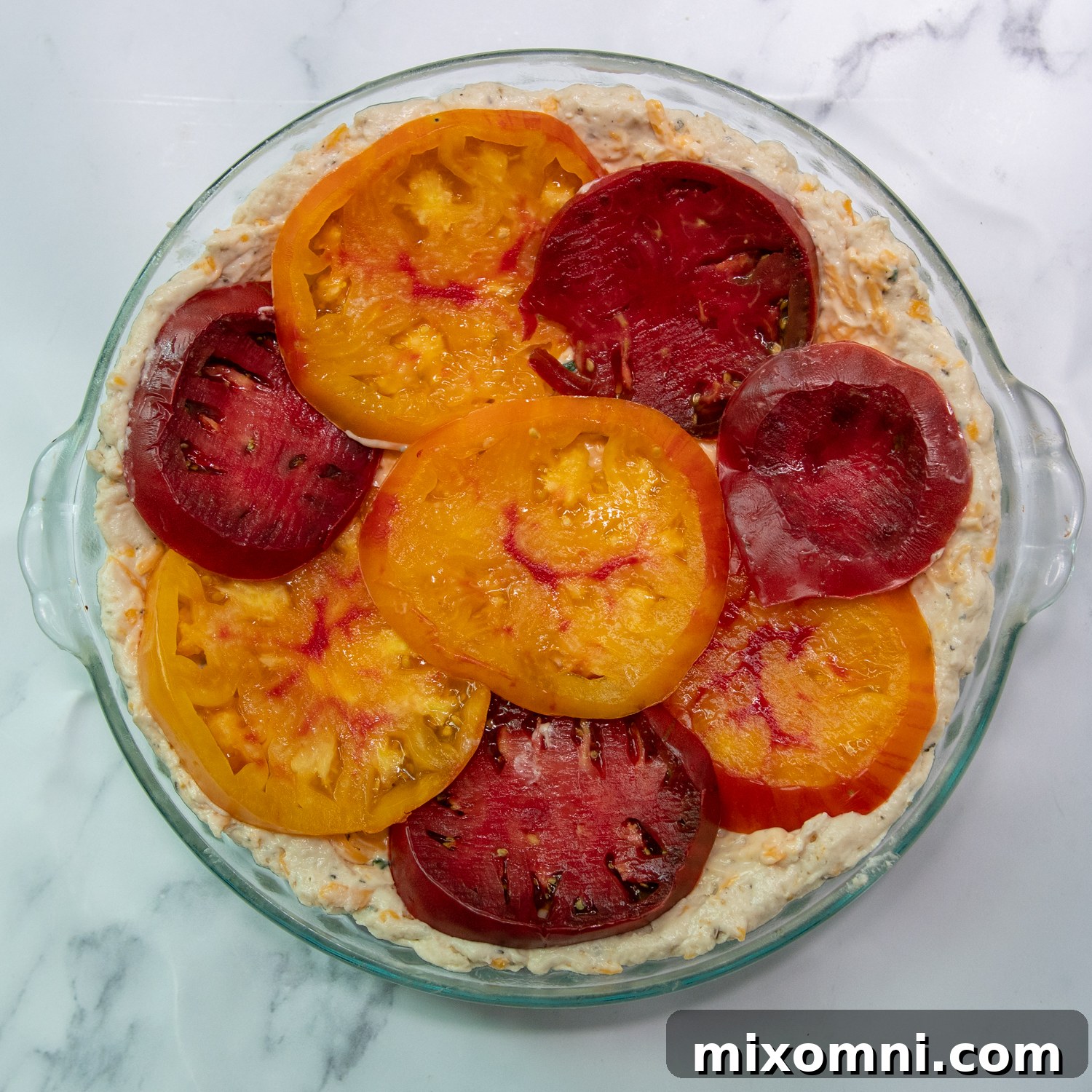 The first layer of cheese-mayo filling and sliced tomatoes arranged in the pie crust.
