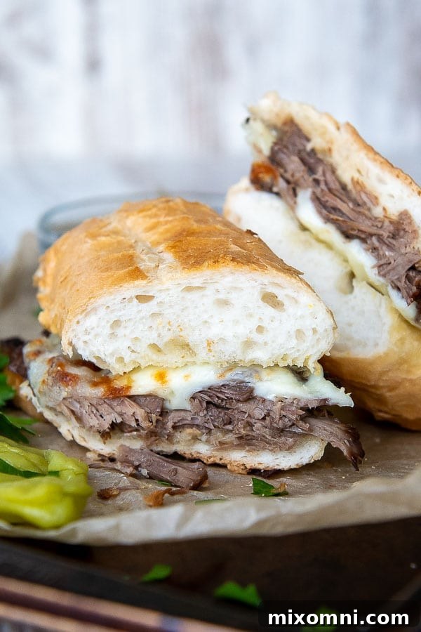 Perfectly sliced, tender roast beef generously topped with melted provolone cheese, ready to be placed onto a sturdy gluten-free bun. The sandwich rests on a baking sheet, hinting at its delicious preparation.
