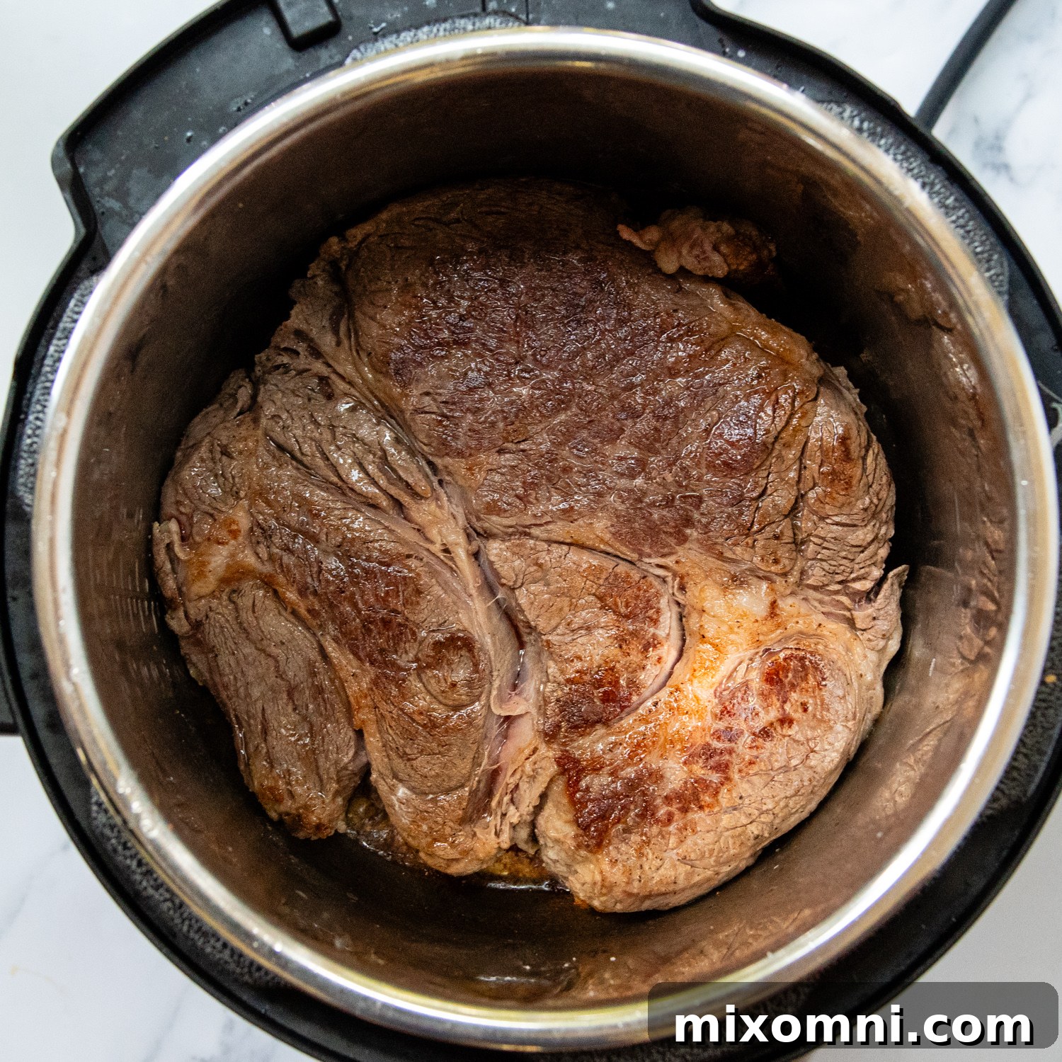 A large cut of beef being expertly seared in a heavy-bottomed pot, achieving a rich brown crust.