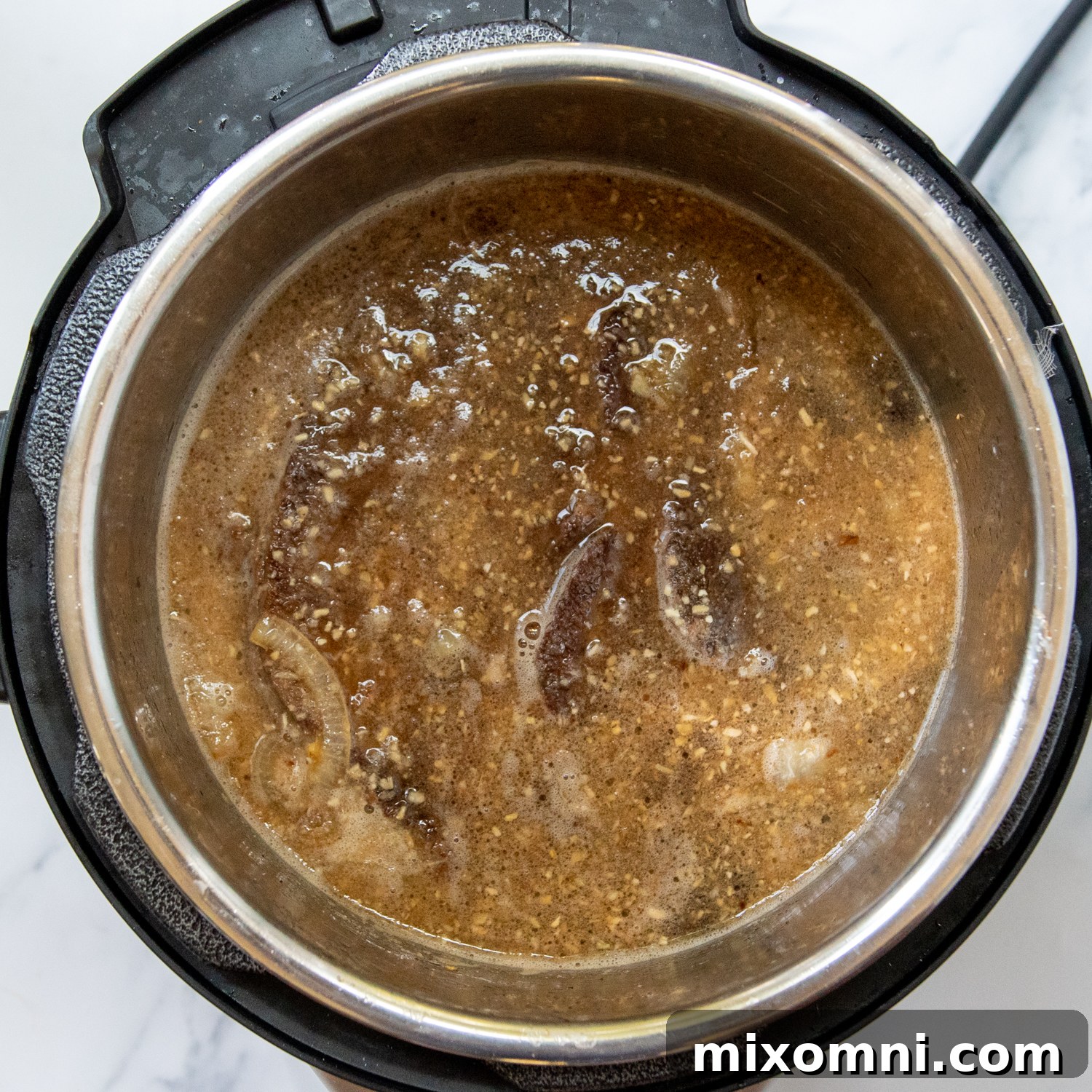Liquids and seasonings being poured over the seared beef and onions in a pot, ready for slow cooking or pressure cooking.