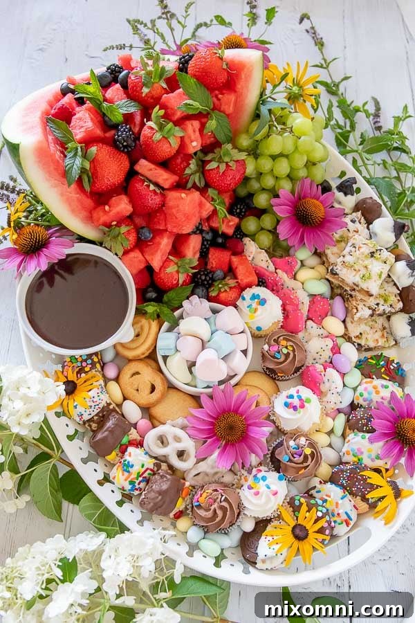 A beautifully arranged dessert platter on a white tray, adorned with fresh fruits, an assortment of sweets, and delicate fresh flowers, ready for entertaining.