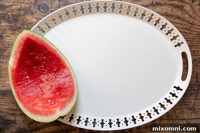The first step in making a dessert plate: positioning a hollowed-out watermelon as a central feature on the board.