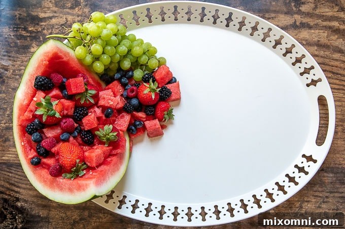 The second step in creating a dessert platter: filling the hollowed watermelon with an assortment of fresh fruit.