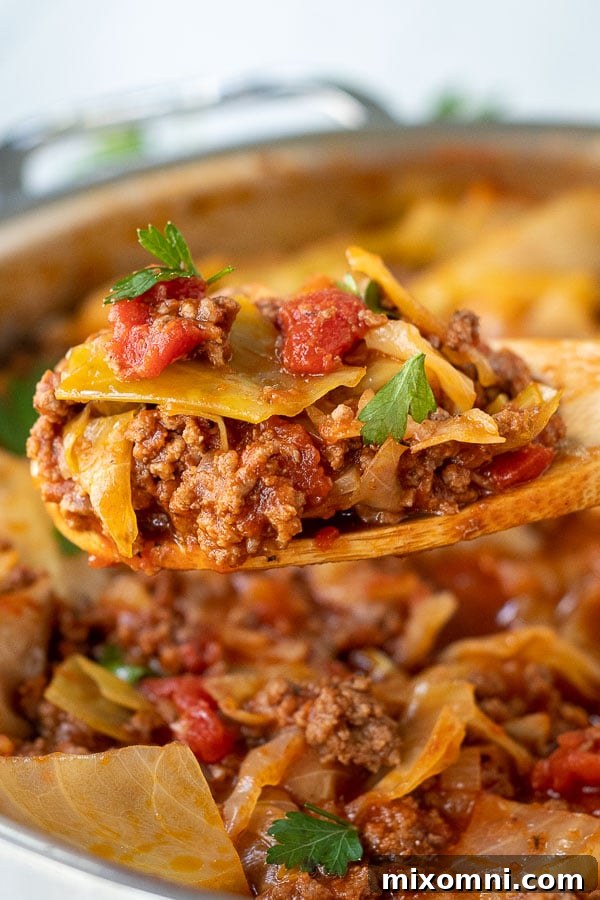 A wooden spoon lifting a generous serving of unstuffed cabbage rolls from a pot, showcasing the rich texture and vibrant colors.