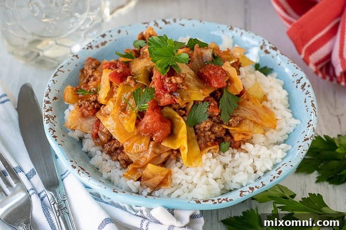 A serving of unstuffed cabbage rolls neatly arranged in a blue bowl, served over a bed of fluffy white rice, ready for a comforting meal.