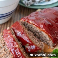 instant pot meatloaf sliced on a wooden board with a bowl of mashed potatoes in the background