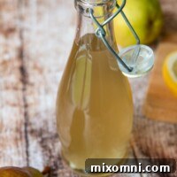 a bottle of ginger simple syrup in a glass bottle with a fresh pear next to it