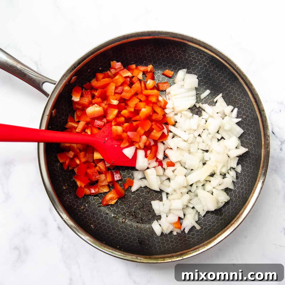 Diced onions and bell peppers simmering in a skillet alongside crumbled, browned breakfast sausage.
