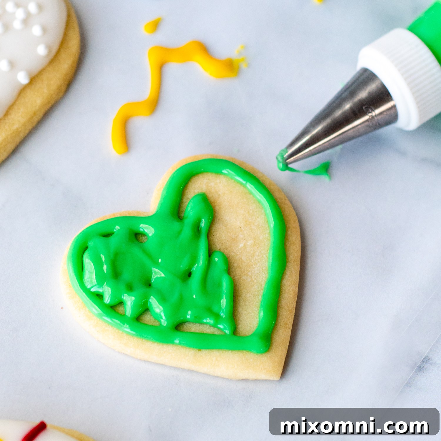 A collection of vibrant, freshly iced sugar cookies showcasing various decorating techniques, including outlining, flooding, and immediate application of sprinkles.
