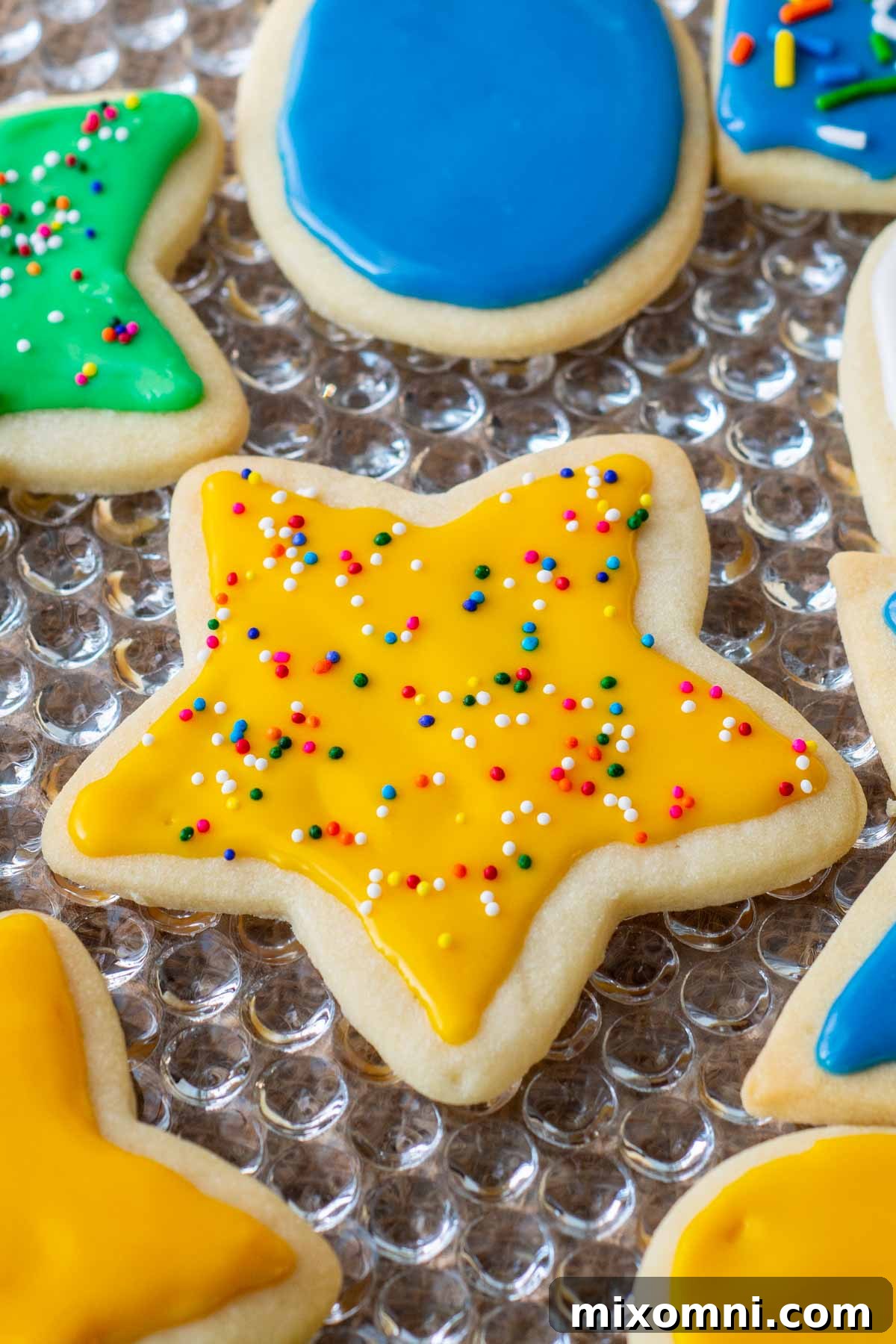 A beautifully arranged platter showcasing an assortment of freshly decorated sugar cookies, each adorned with glossy, hardened icing and festive sprinkles, ready for sharing.