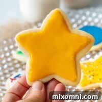 A close-up of a yellow star cookie held against a soft background, showing the perfectly smooth and glossy hardened icing.