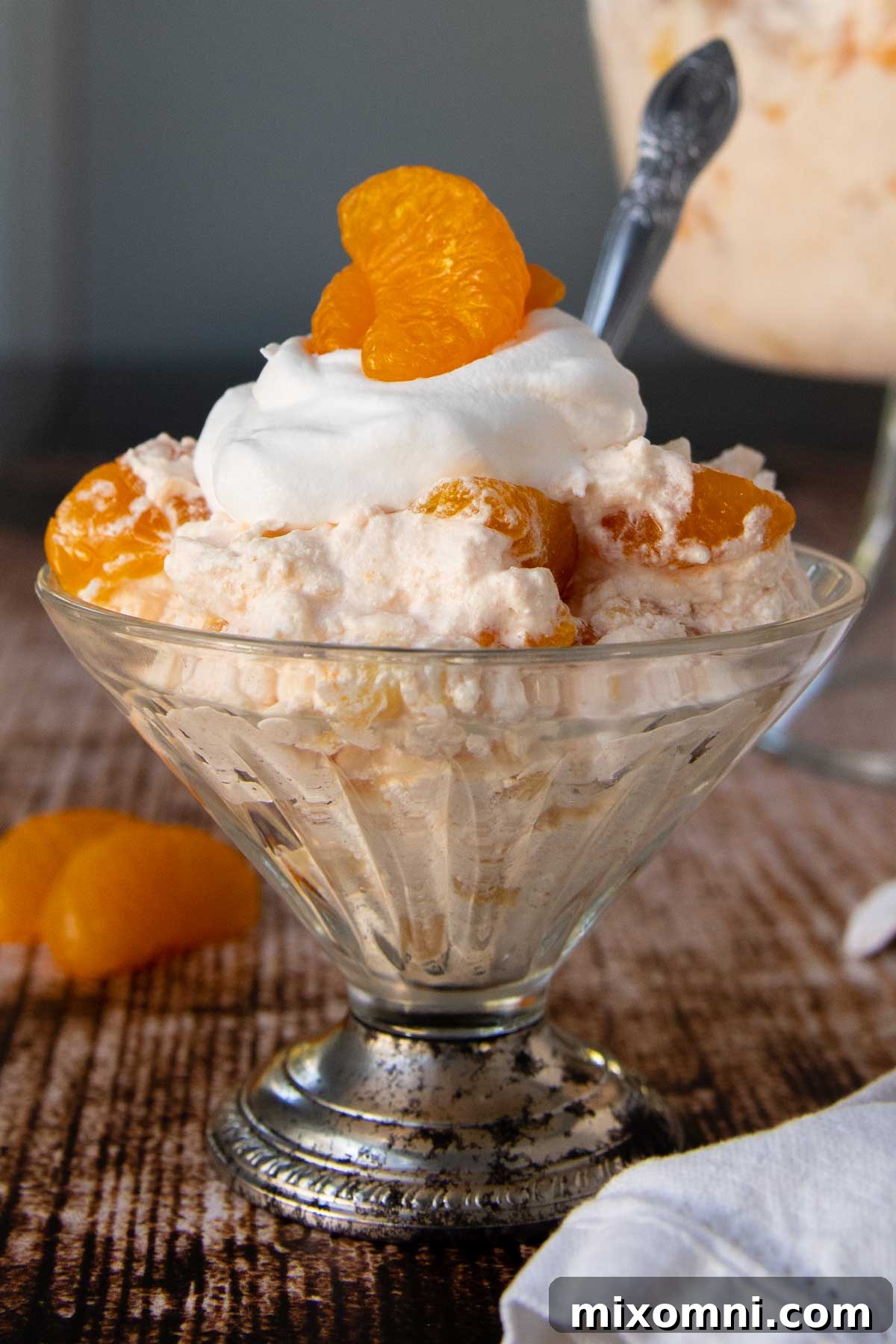 Orange jello salad in an old-fashioned serving dish with a mandarin orange on top, ready to be served.