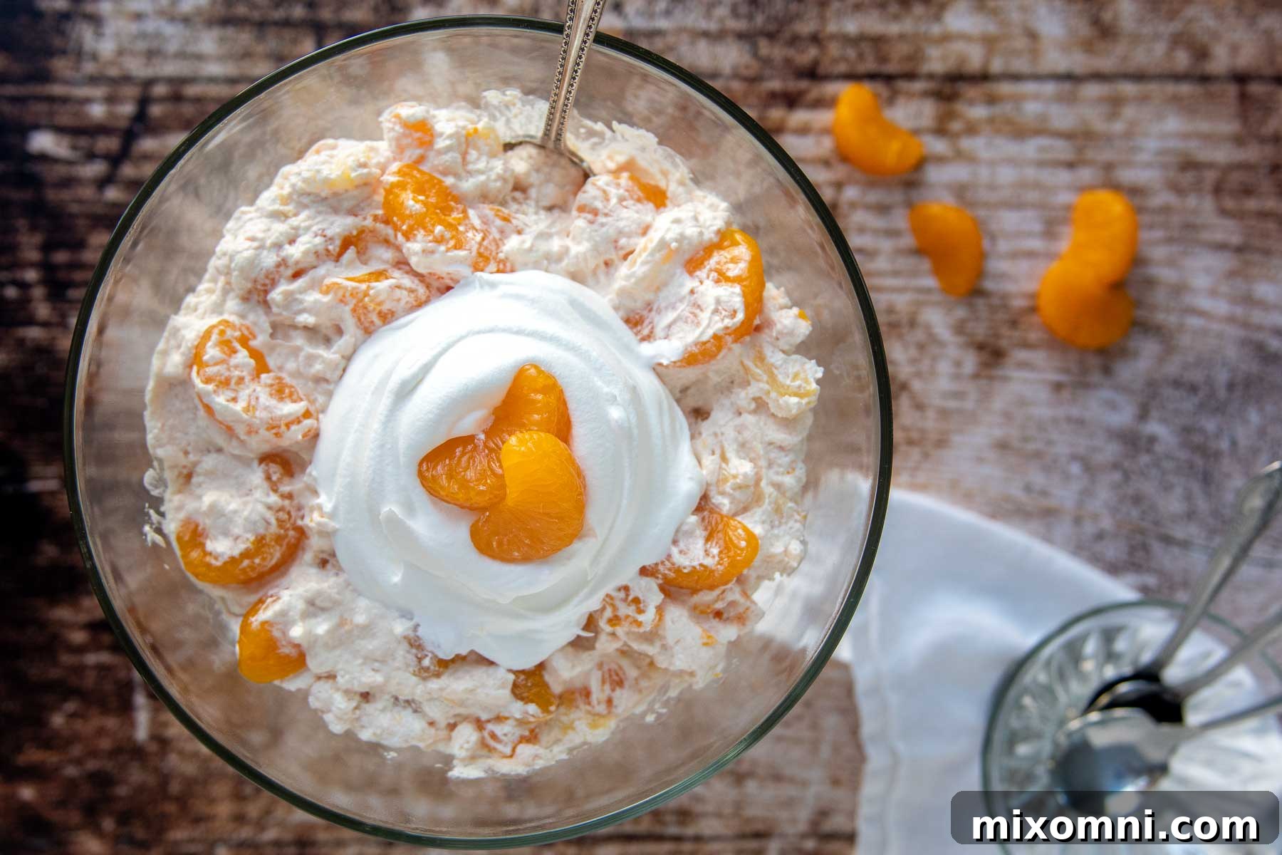 Overhead shot of orange jello salad in a large glass serving bowl, garnished and ready for a party.