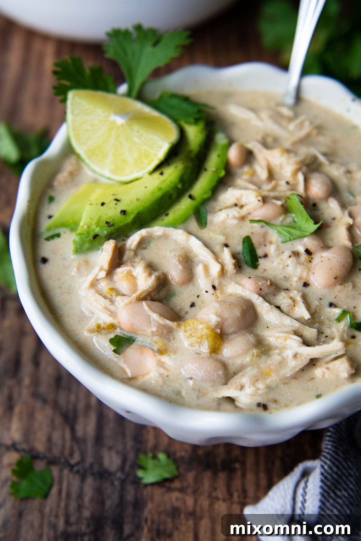 A bowl of white chili with spoon resting in it