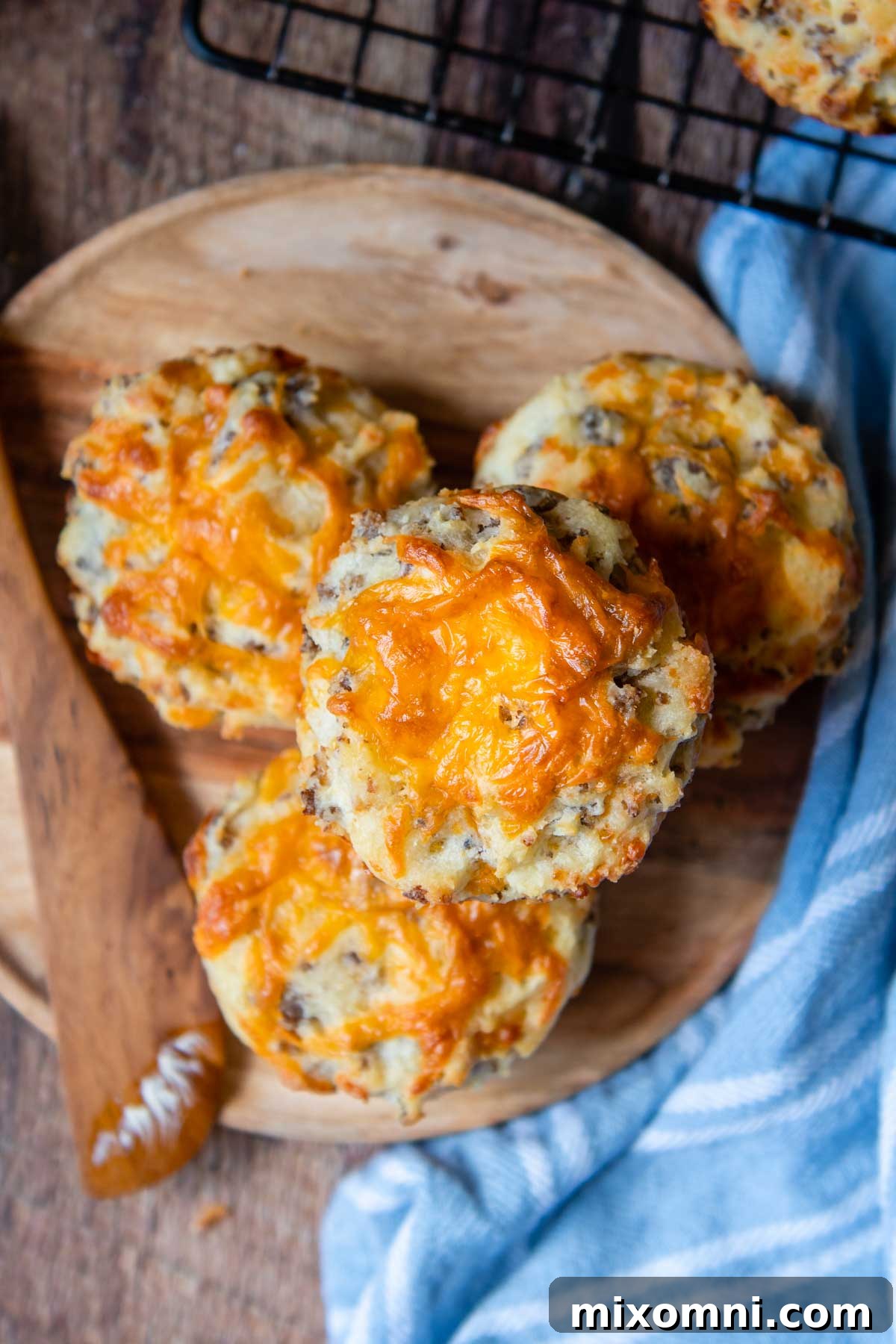 Overhead shot of freshly baked sausage muffins with golden-brown tops and melted cheddar cheese, arranged enticingly on a cooling rack.