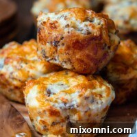 Two cheesy sausage muffins stacked on a wooden plate, ready to be enjoyed.