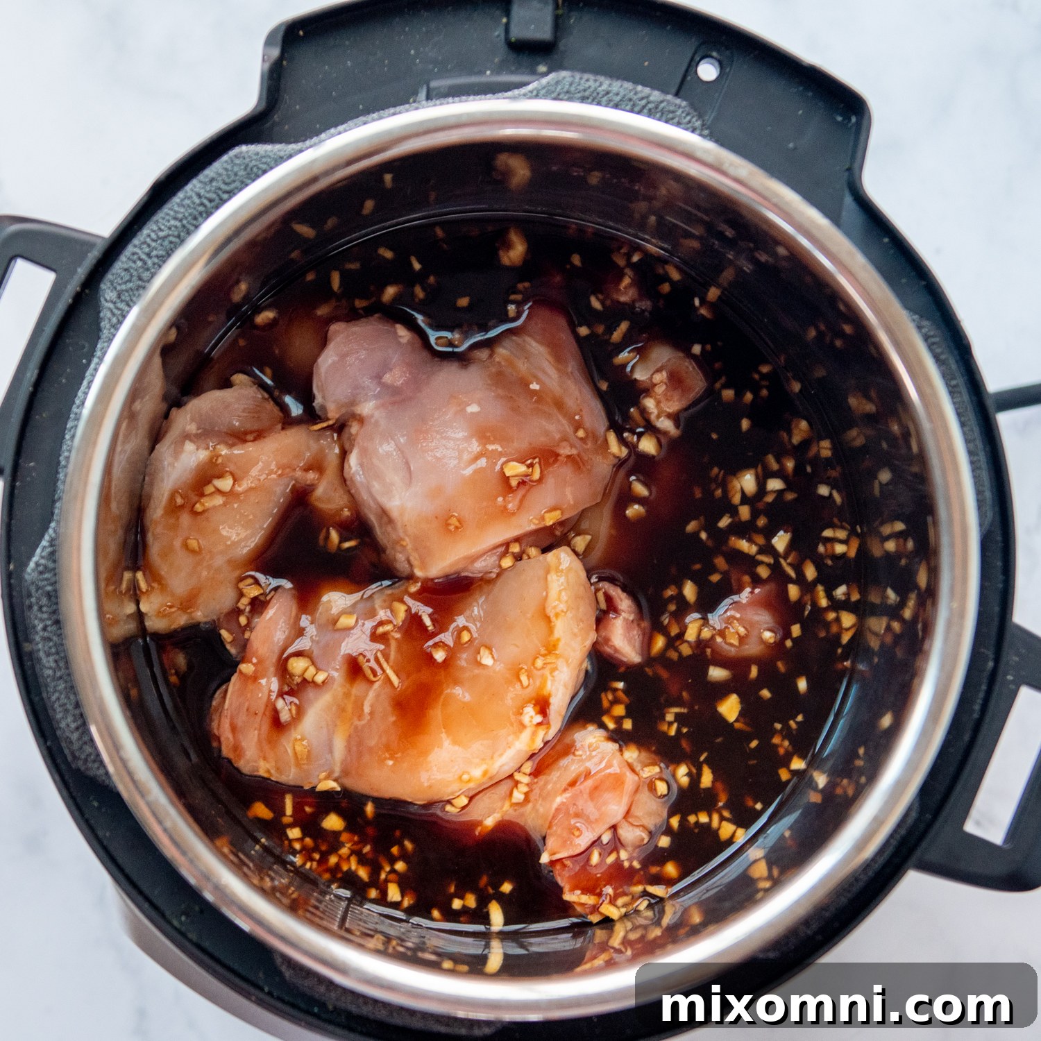 chicken thighs in an Instant Pot with the sauce poured over them.