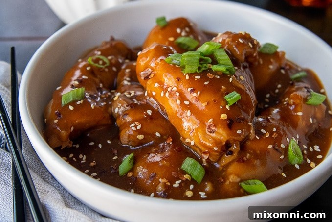 honey soy chicken thighs with sauce in a white bowl with chopsticks laying next to it