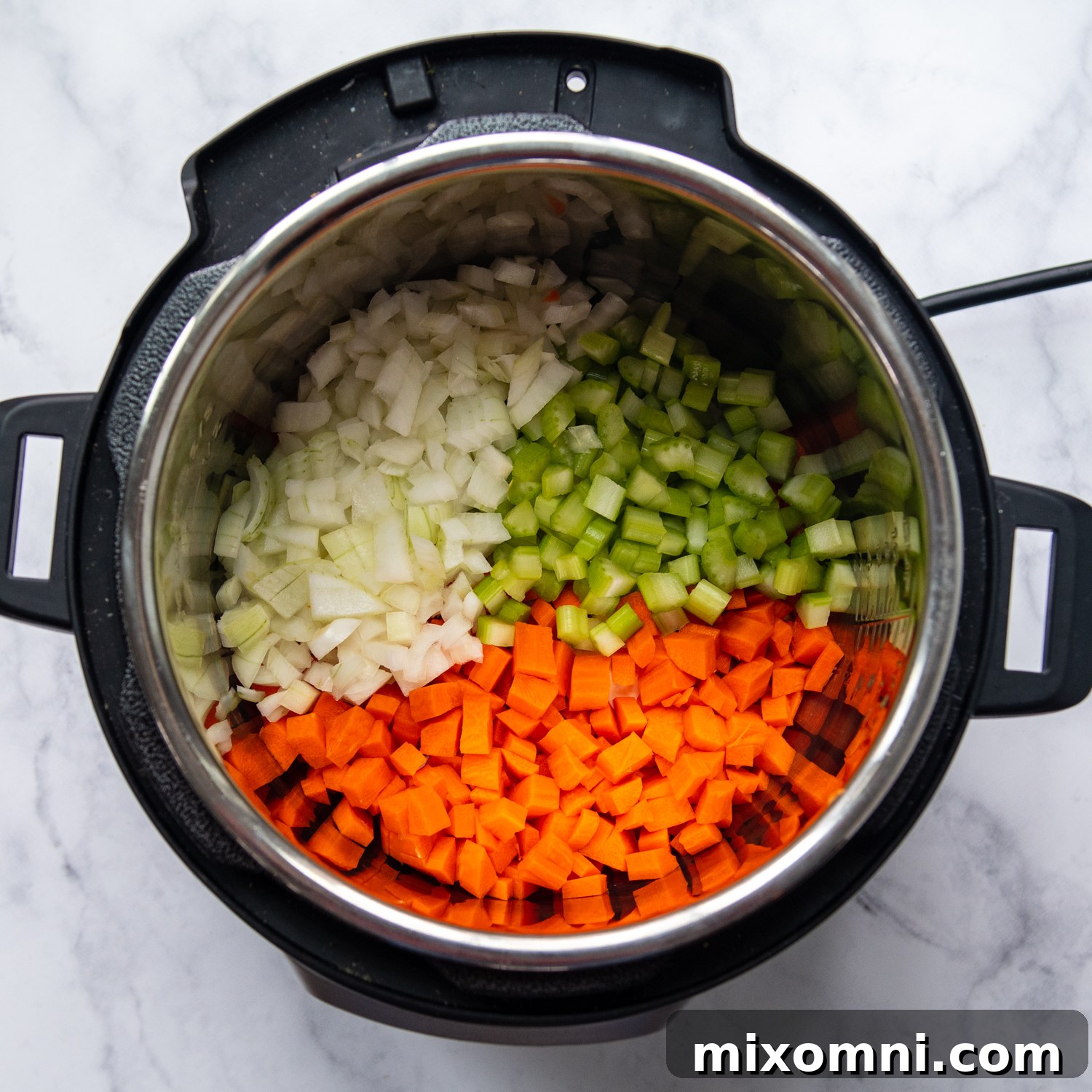 Freshly chopped onions, carrots, and celery being sautéed in butter in an Instant Pot, forming the aromatic base of the soup.