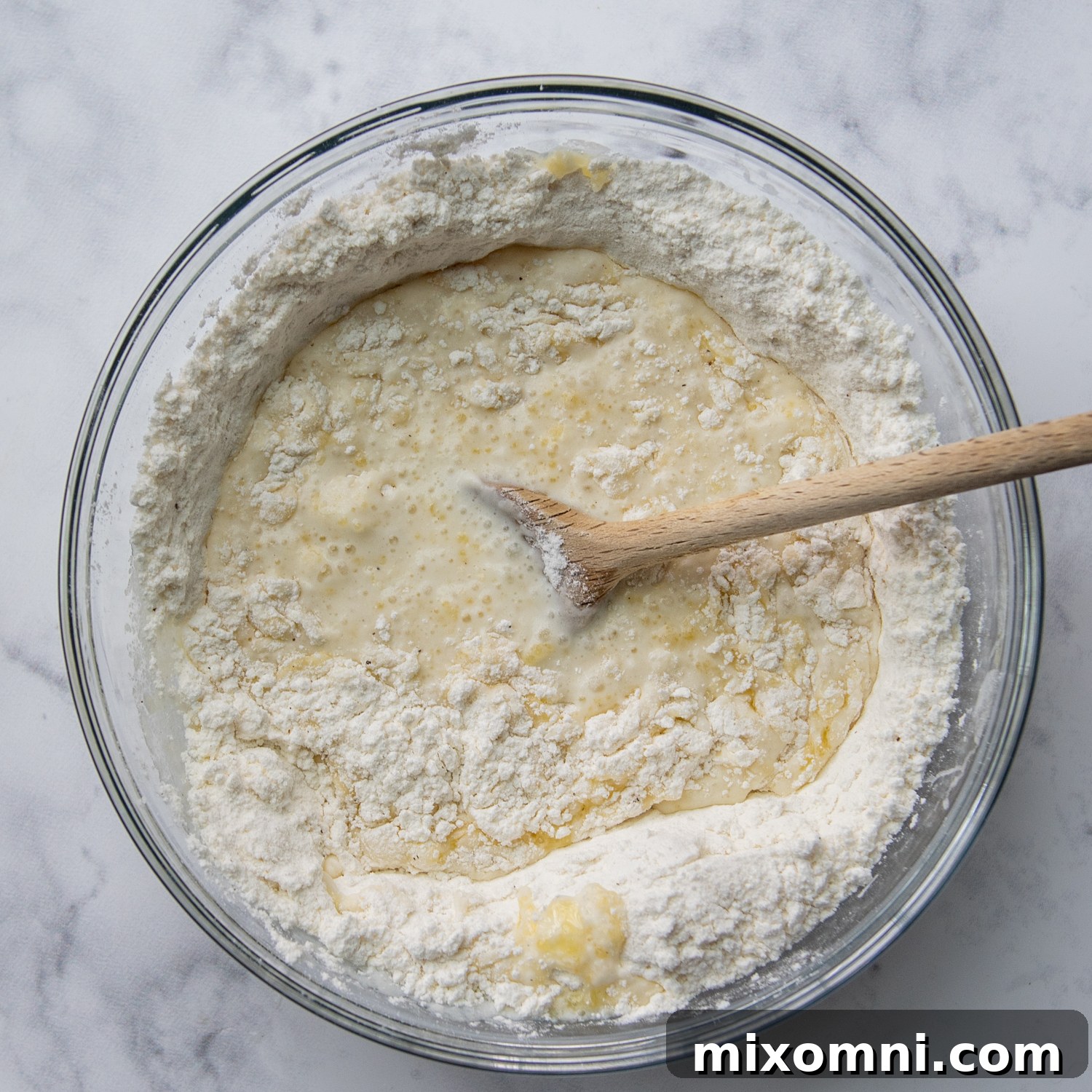 Dry ingredients for gluten-free dumplings (flour, baking powder, salt, pepper) being mixed in a bowl with melted butter and milk.