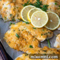 parmesan crusted tilapia on a baking sheet with lemon slices on top