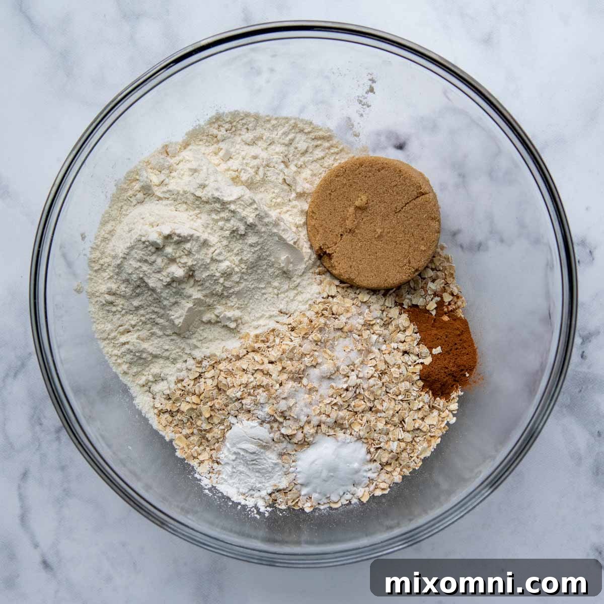 Dry ingredients for applesauce oatmeal muffins in a large mixing bowl, ready to be combined.