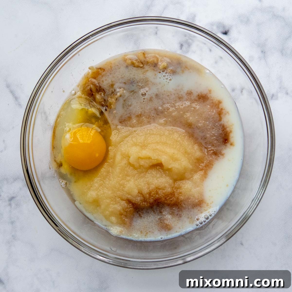 Wet ingredients, including applesauce and mashed banana, in a separate bowl, whisked until smooth.