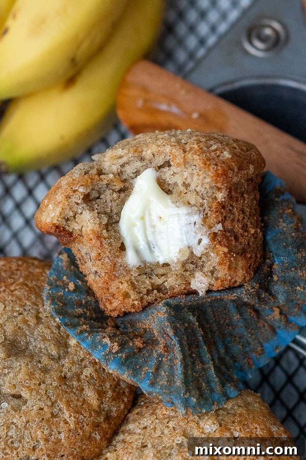A gluten-free banana muffin with a bite taken out, showing its fluffy interior and melted butter on top.