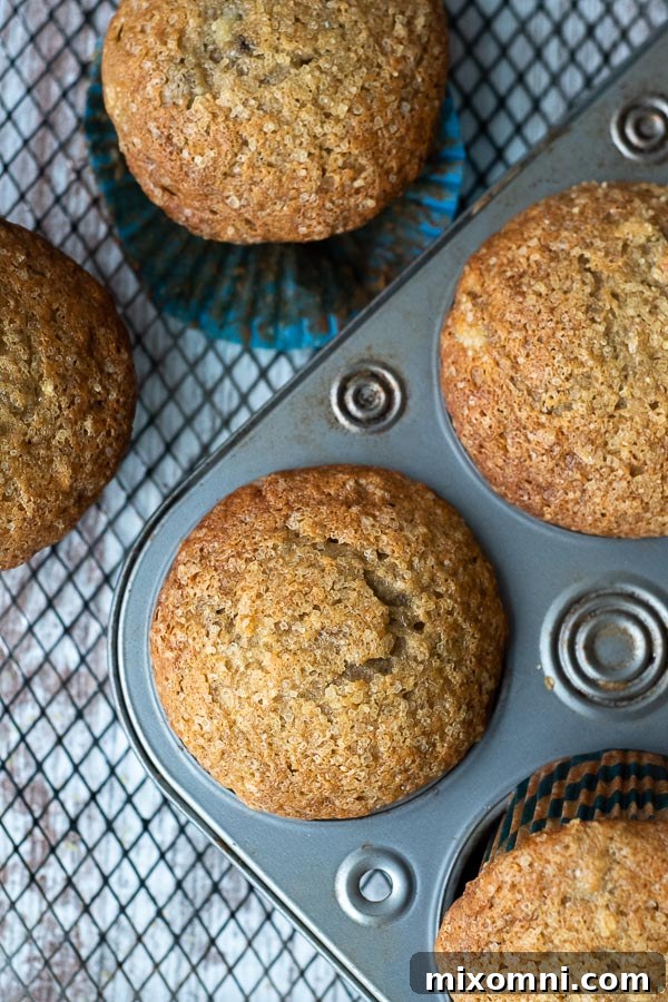 Overhead shot of freshly baked gluten-free banana muffins with domed tops in a muffin tin on a cooling rack.