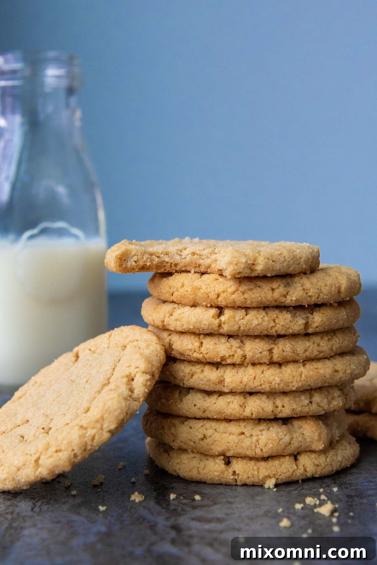 A charming stack of freshly baked almond flour peanut butter cookies beside a cool glass of milk, inviting a delicious break.