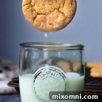 A delicious almond flour peanut butter cookie gracefully being dunked into a glass of fresh milk.