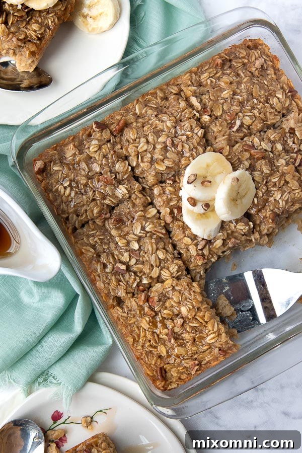 An overhead view of a banana baked oatmeal casserole, perfectly sliced into squares with individual serving plates arranged around it.