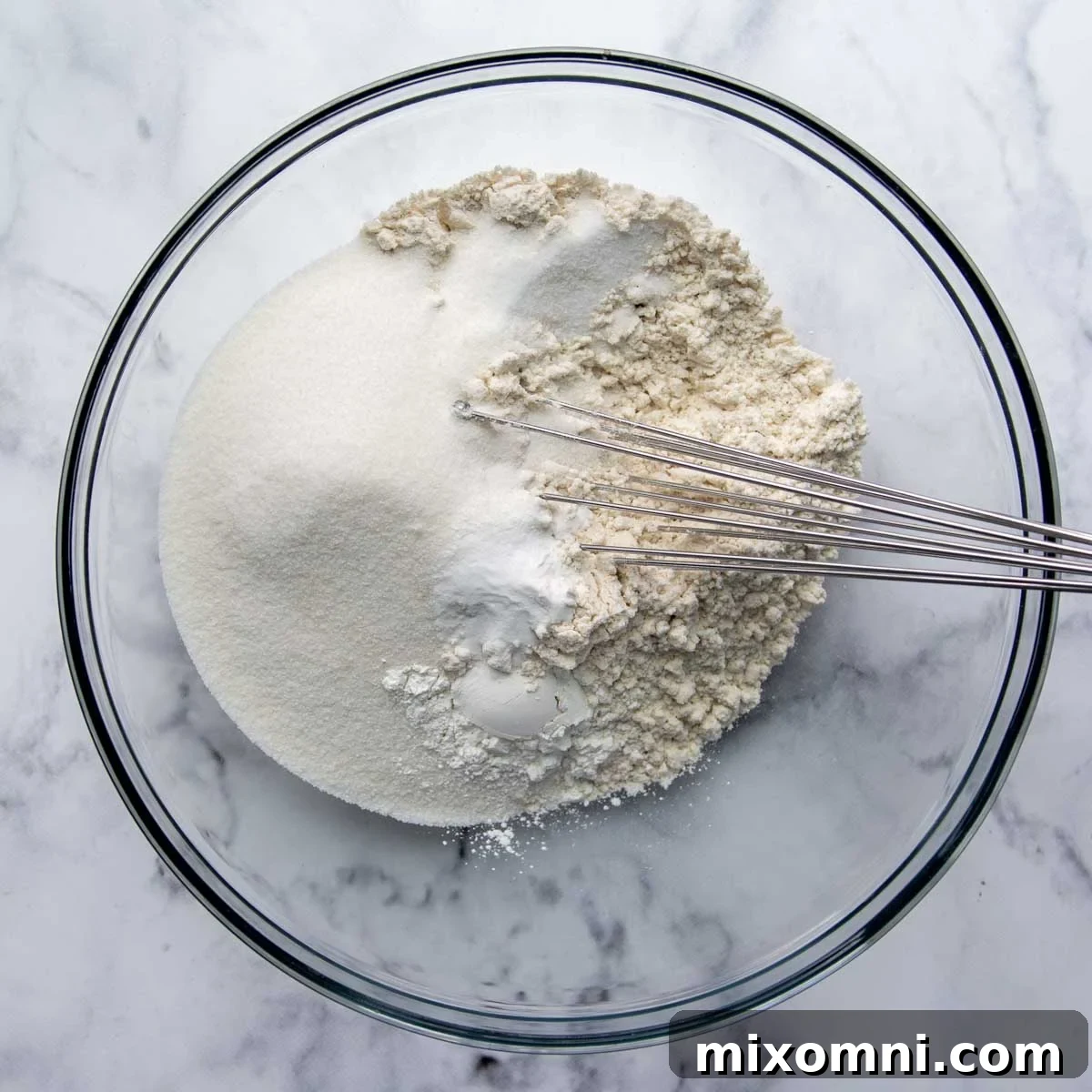 Dry ingredients (gluten-free flour, sugar, baking powder, baking soda, salt) in a glass bowl, ready to be mixed.