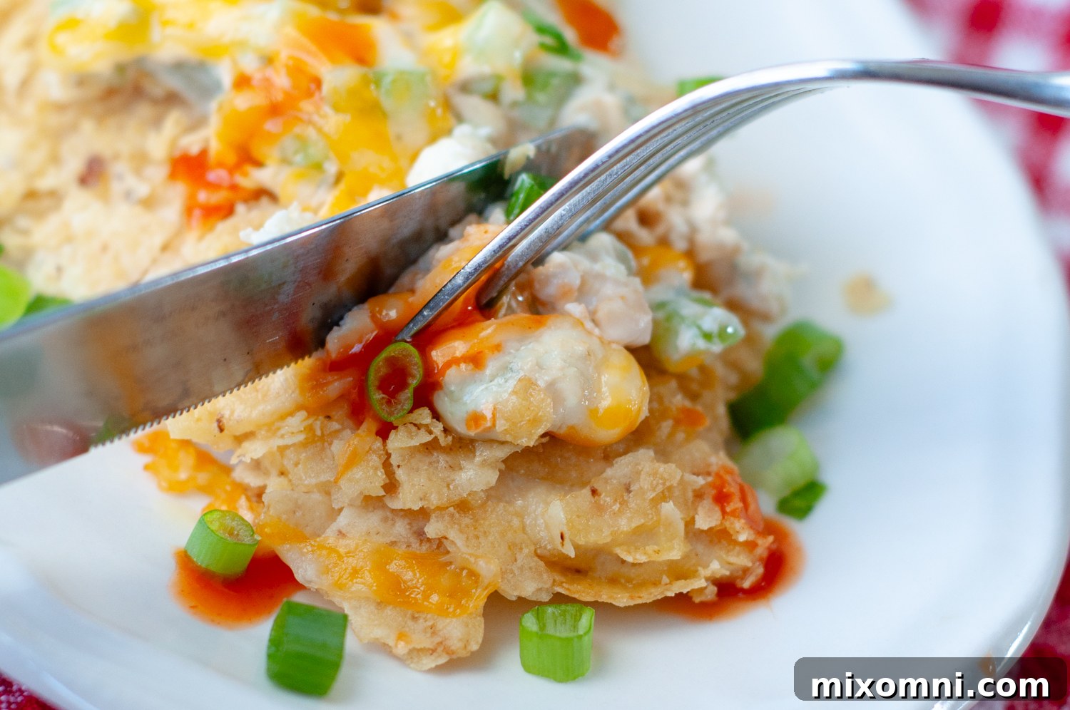 A fork cutting into a succulent serving of baked Buffalo Tortilla Crusted Chicken, showcasing the crispy exterior and creamy topping.