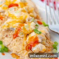 Baked buffalo chicken on a white plate with a fork resting nearby, ready to be eaten.