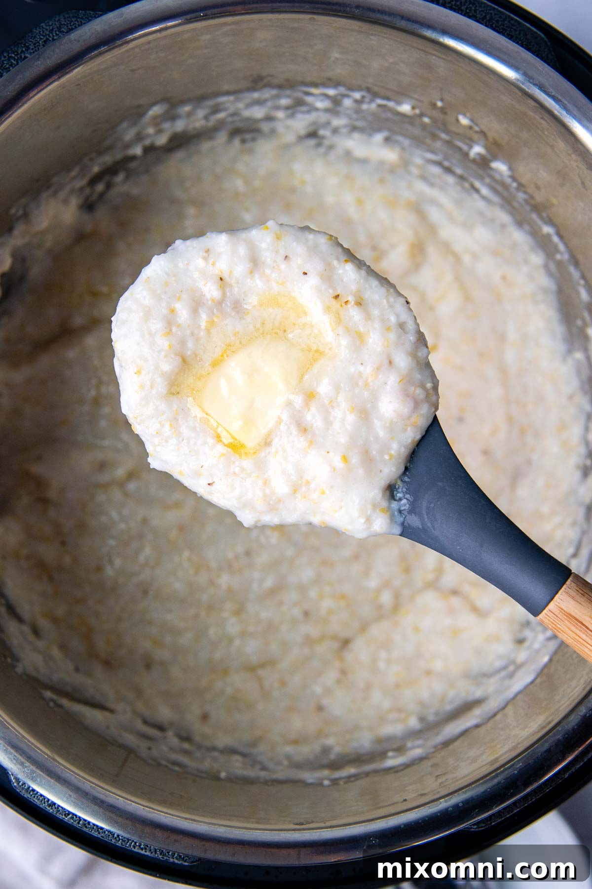 A scoop of rich, creamy grits with melted butter on top, lifted from an Instant Pot, showcasing its perfect texture.