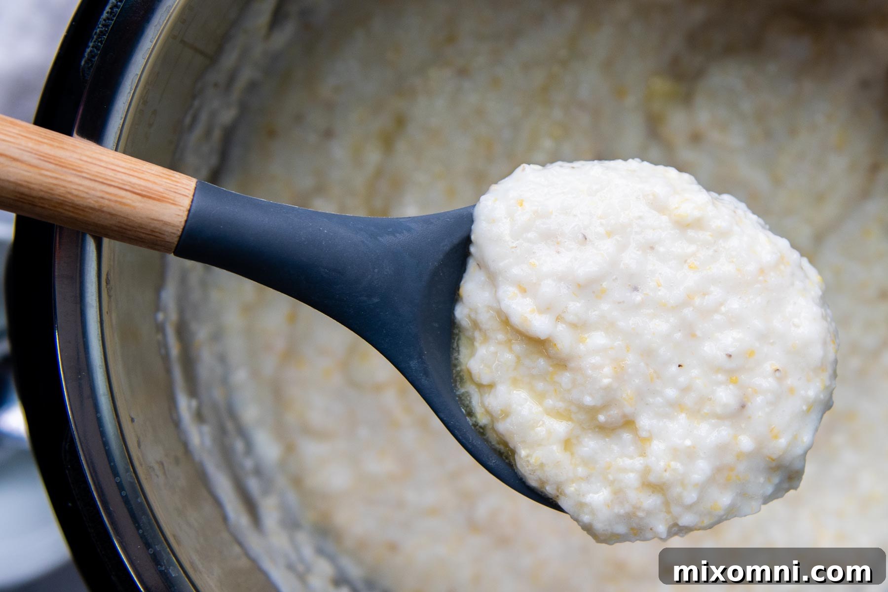 A ladle holding up rich, creamy grits, demonstrating the perfect texture achieved after cooking in an Instant Pot.