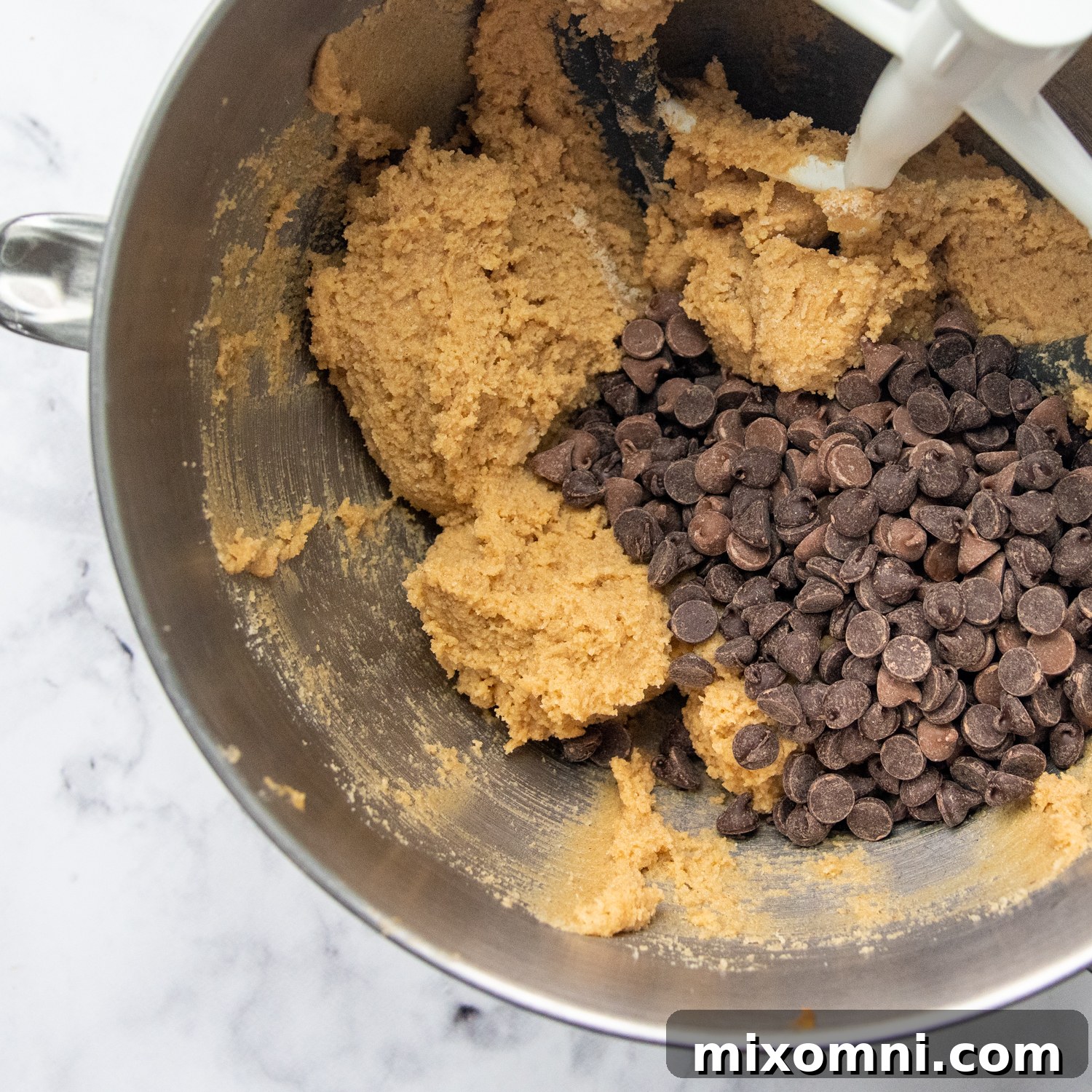 Creamy cookie dough with chocolate chips waiting to be stirred in, showcasing the perfect texture before baking.