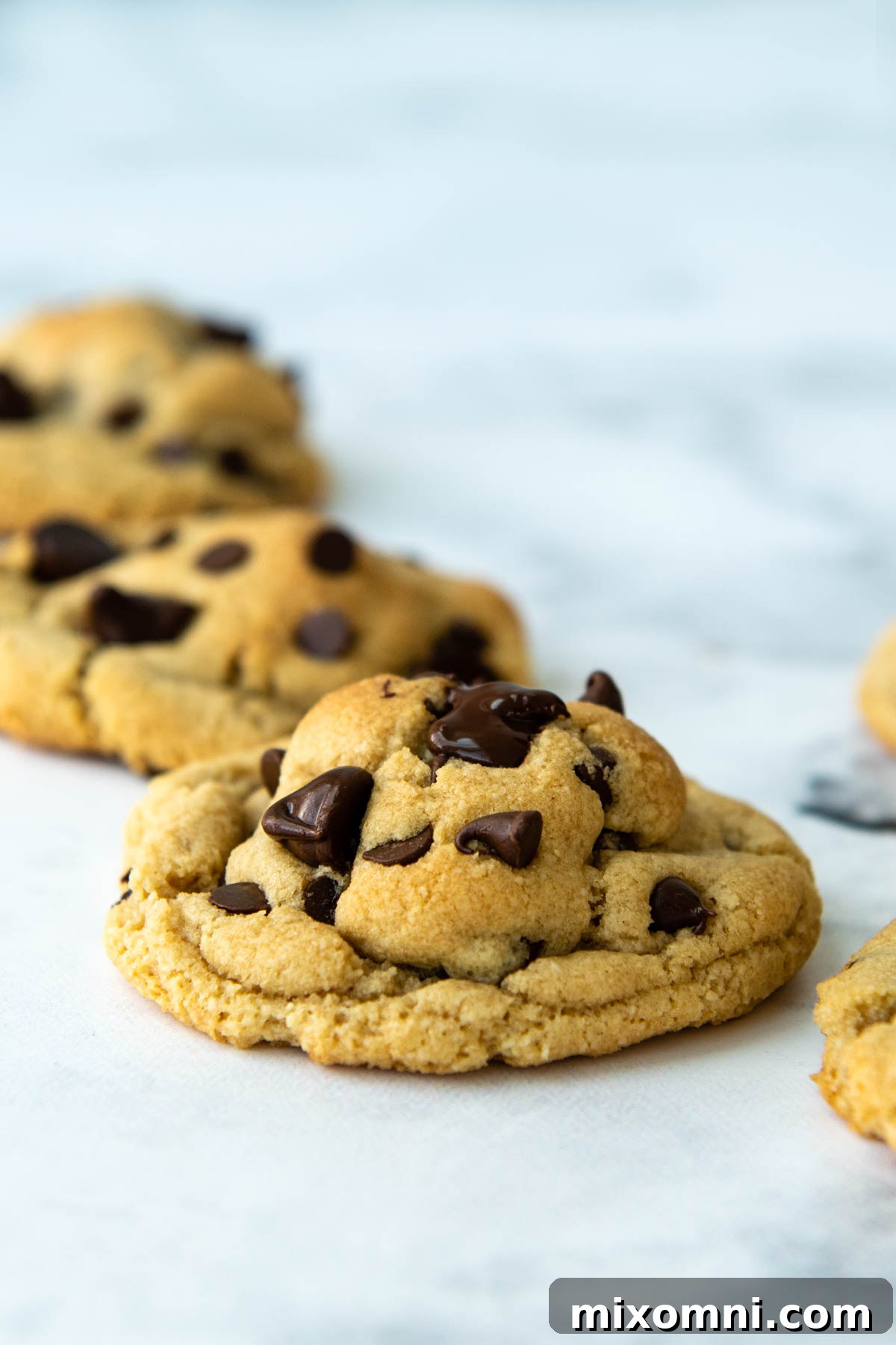 A diagonal line of freshly baked almond flour cookies on a white surface, showing their beautiful bakery-style ridges.