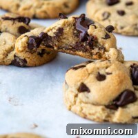 A bitten almond flour chocolate chip cookie resting on two others.