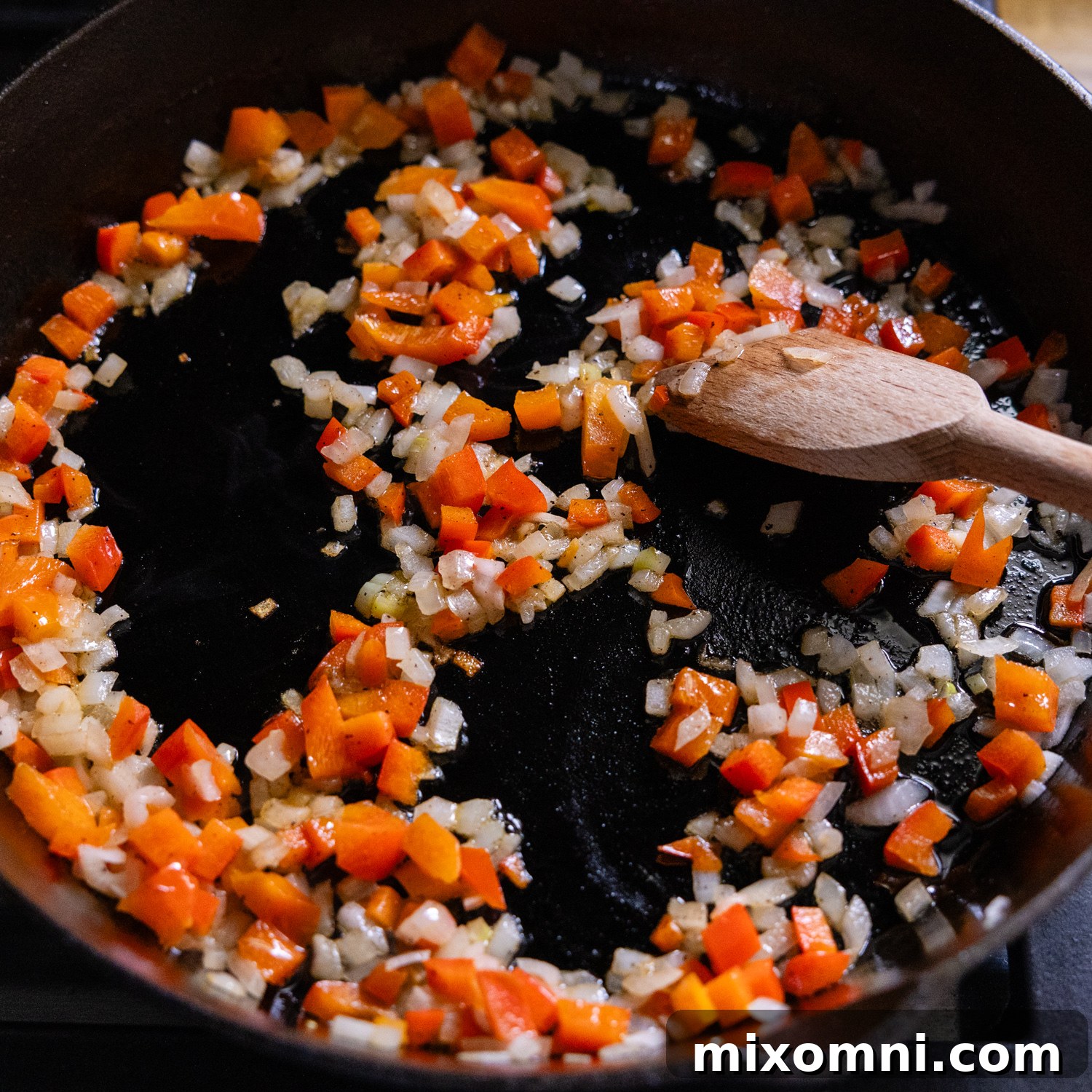 Diced onions and bell peppers being sautéed in a skillet.