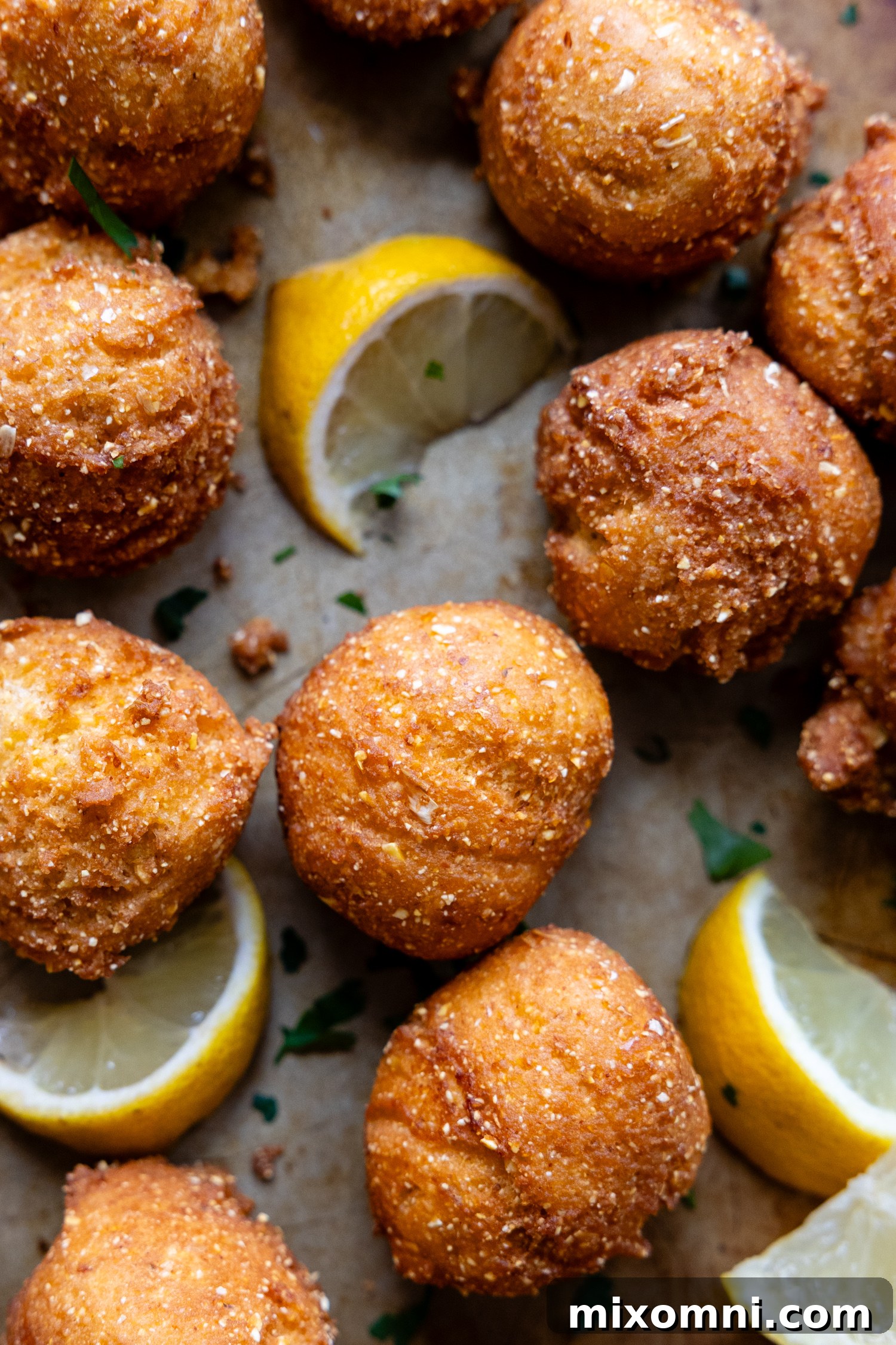 Hush puppies and lemon wedges on a pan.